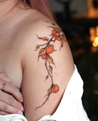 a woman with an orange branch tattoo on her shoulder