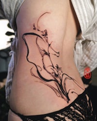 a woman's back with a tattoo of a woman in black ink